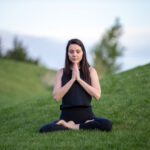Prenatal Yoga - woman in black tank top and black pants sitting on green grass field during daytime