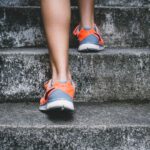Strength Running - person wearing orange and gray Nike shoes walking on gray concrete stairs