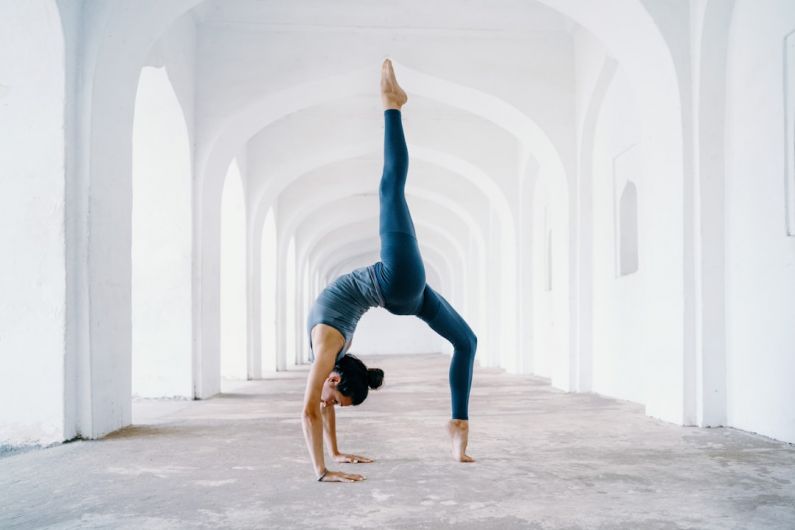 Yoga Pose - woman in blue leggings and black tank top doing yoga