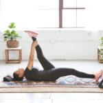 Yoga Recovery - woman in black tank top and black leggings lying on black and white floral area rug