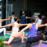 Group Fitness - woman in white tank top and pink leggings doing yoga