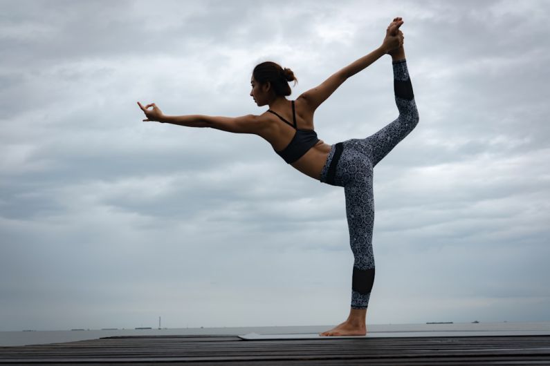 Power Yoga - woman in black sports bra and blue leggings doing yoga during daytime